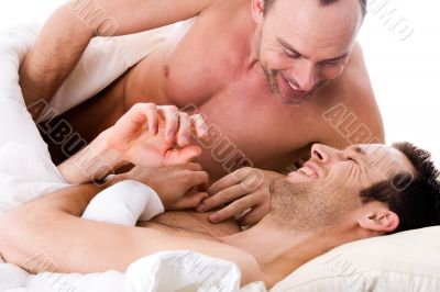 Smiling men couple in bed