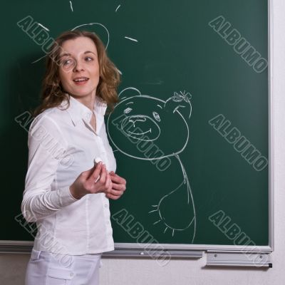 Young woman is standing at the blackboard