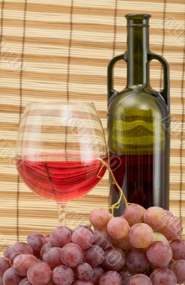 Glass bottle, goblet and grape