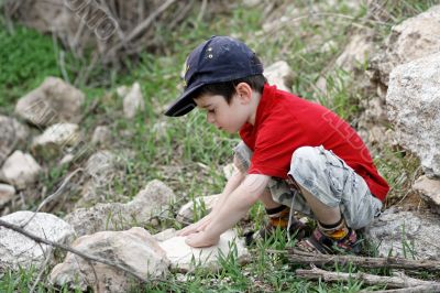 Little boy squatting on stones
