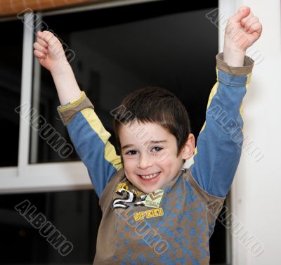 Little boy rises his arms in a victory sign