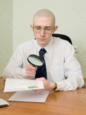 Boss with a magnifier on a workplace