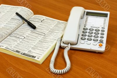 White telephone on wooden desk.