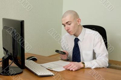 Businessman with a magnifier on a workplace