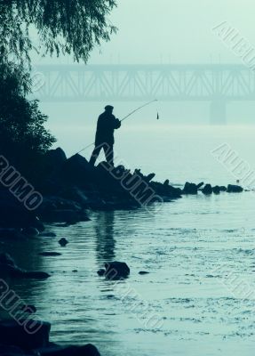 Silhouette of alone fisher near sunset river