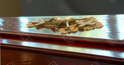 golden Jesus crucifix on dark wooden coffin top