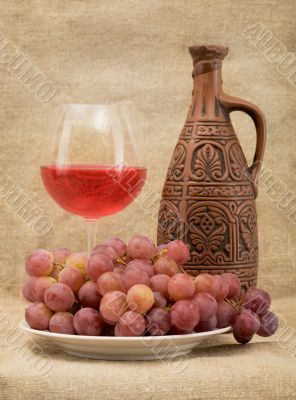Ceramic bottle, goblet and grapes