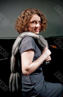 young girl sitting near piano with fur scarf