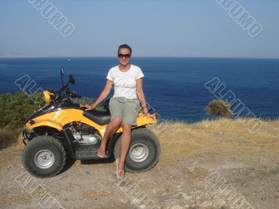 Pretty girl on quadricycle near the sea