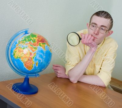 Young man with a magnifier and globe