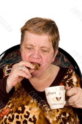 elderly woman is drinking coffee and eating a cookie
