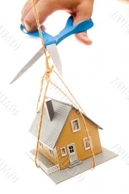 Hand with Scissors Cutting String Holding House