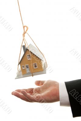 Businessman`s Hand Under Dangling House