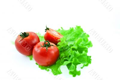 two and half red tomatos on leaves of lettuce