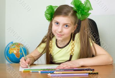 Girl sitting at a table with pencils