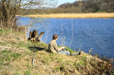 Fisherman sitting on the river shore