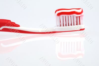 red toothbrush with toothpaste and reflection