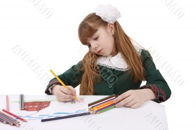 Schoolgirl is painting in bright colours pencils.