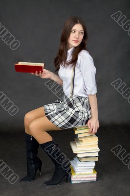 Young woman sits on a pile of books