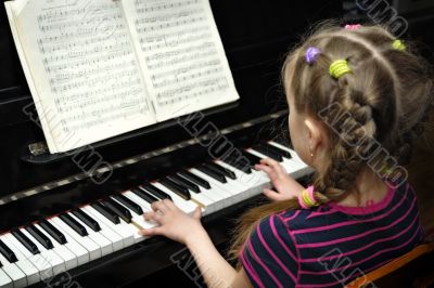 child plays on piano, lesson of the music