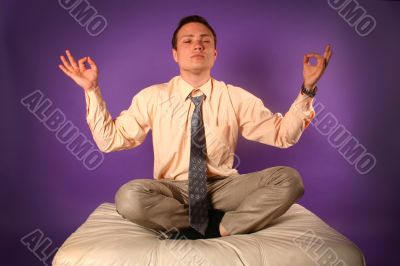 Young businessman meditating on sofa