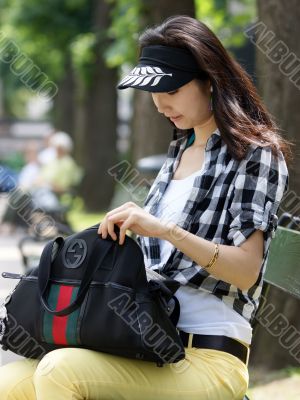 Young woman looking for something in your handbag