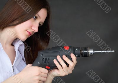 Young beautiful girl with drill in hands