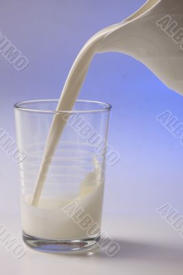 milk pouring in glass from pitcher