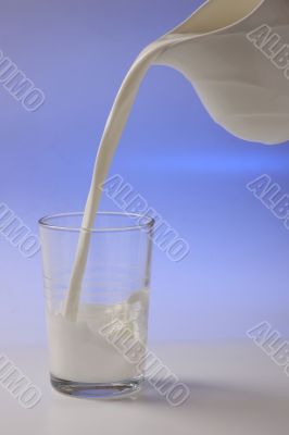 milk pouring in glass from pitcher