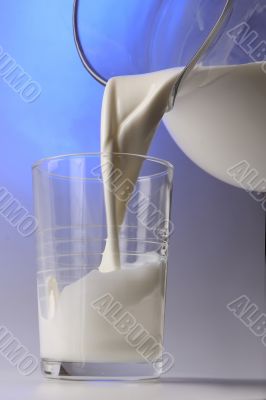 milk pouring in glass from pitcher