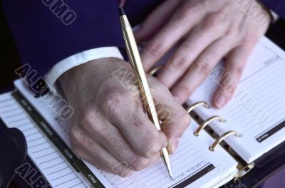 Close up of Man`s Hands Writing in Planner