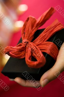 Hand holding gift with red bow