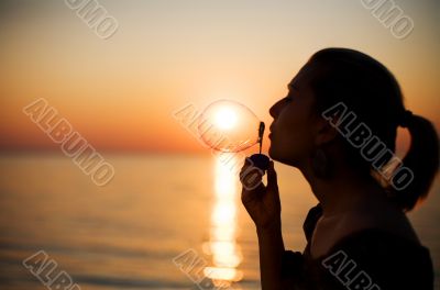 girl making soap bubbles over sunset