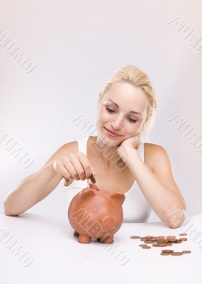 Young lady looking at pink piggy bank