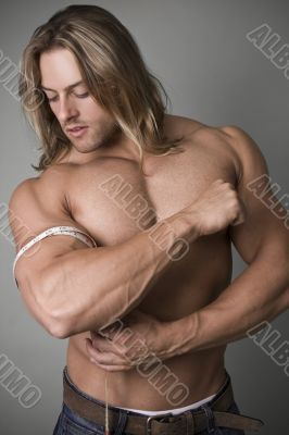 A bodybuilder measuring the increase in his bicep