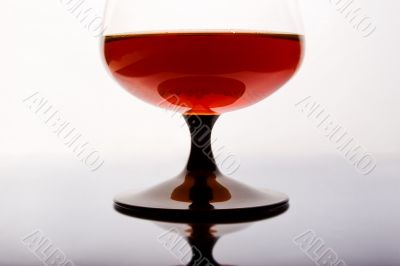 Glass of cognac standing on mirror table.