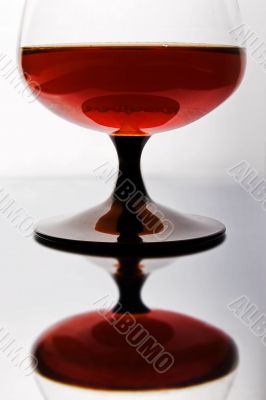 Glass of cognac standing on mirror table.
