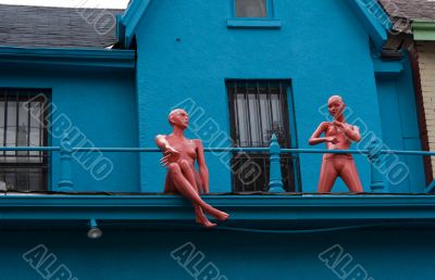 Two pink dolls at the balcony of blue howse