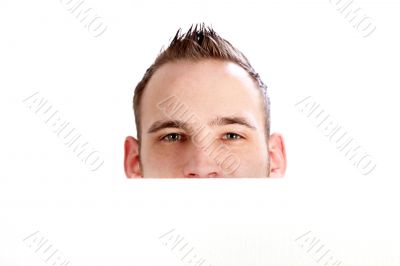 A man looks over a white wall. 