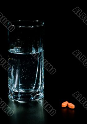 two pills and glass of water