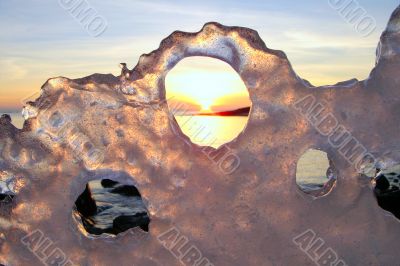 Sunset through ice`s holes