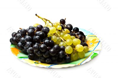 Plate of white and black grapes. Isolated on a white background.