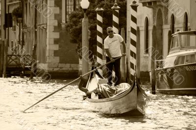 Venetian gondolier floating on central to the channel. Italy.