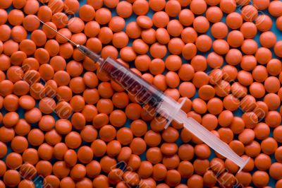 Red Tablet and syringe on blue closeup