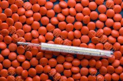 Tablets and thermometer close up on blue