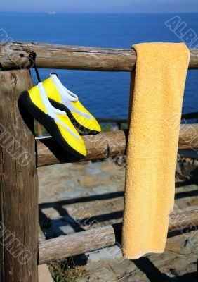 Towel and Beach Shoes on Wooden Fence