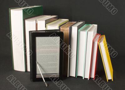 Row of printed books with electronic book reader 