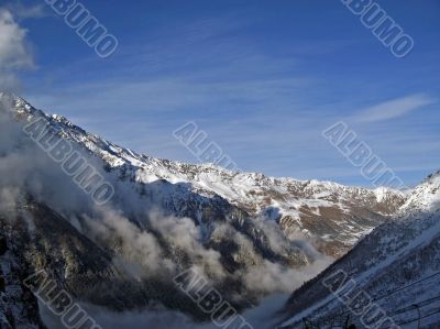 Clouds crawling between the mountains