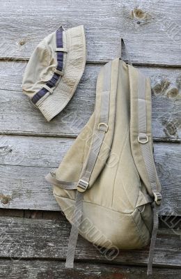 Khaki Hat and Backpack on the Wooden Wall