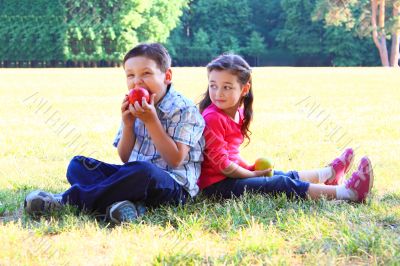 The boy with the girl play sitting on a grass